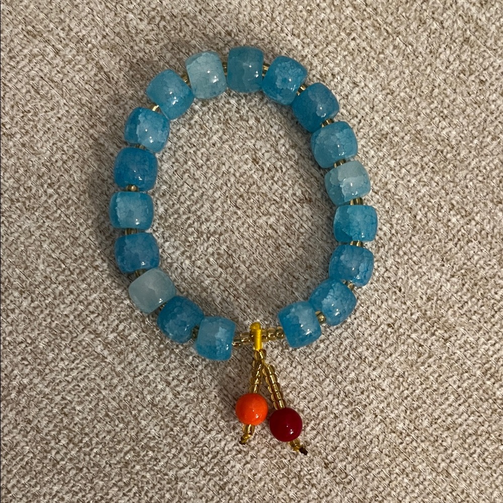 Blue Beaded Stretch Bracelet with Gold Accents and Red-Orange Charm